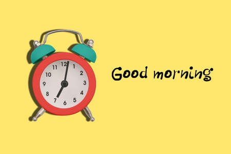 Colorful alarm clock on a yellow background with dough Good morning. The clock shows seven oclock in the morning. Time to get up to workの写真素材