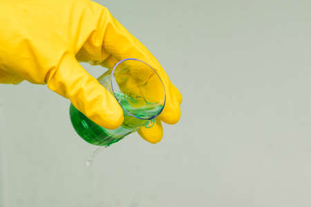 Man in yellow rubber gloves holds a test tube with green liquid. Development of a new drug, chemical experiment. Medical laboratoryの写真素材