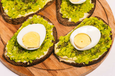 Sandwich with avocado and egg on a wooden board close-up. Food for breakfast, lunch or dinner. Healthy food, vegetarian snacks. Top view, flat layの写真素材