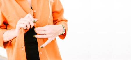 Woman is unbuttoning her orange shirt. A young girl takes off her clothes on a white background with...