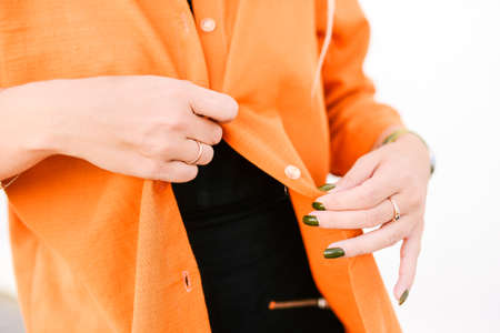 The girl takes off her clothes. Orange jacket. Fashion and style concept