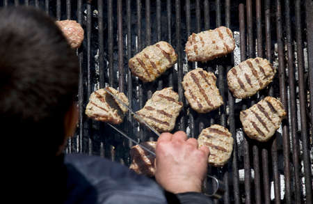 Kebapcheta and meatballs on charcoal grill, human with grill tongsの写真素材