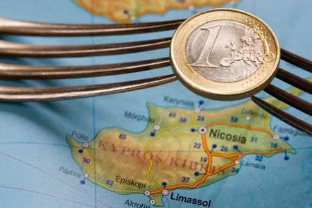 Two forks hold one euro coin over Cyprus map の写真素材