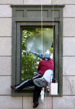 A man hanging on a rope and washing a windowのeditorial素材