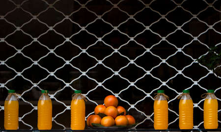 Freshly squeezed orange juice and several oranges arranged on a rowの写真素材