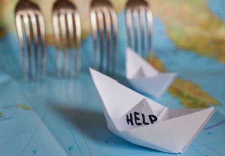 White paper boat onto world map with "Help" sign on it.の写真素材