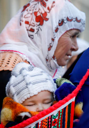 RIBNOVO, BULGARIA - FEBRUARY 14: A child sleeps in a traditional woolen sack from the back of its...