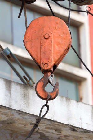 Rusty old red crane hook seen outside.の写真素材