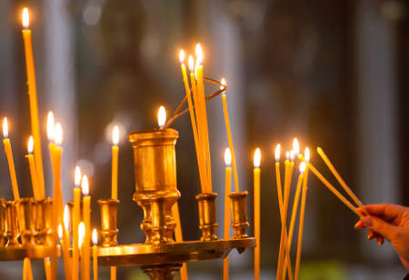 Woman hand lighting candles in a church.の写真素材