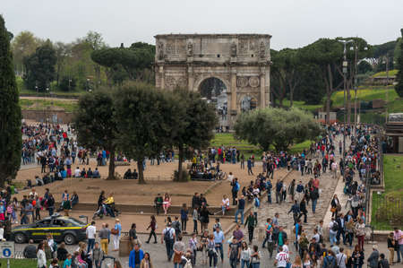 ROME, ITALY - APRIL 7: Tourists visiting Arco de Constantino (Arch of Constantine) and Colosseum. The arch was erected by the Roman Senate to commemorate Constantine victory over Maxentiusのeditorial素材