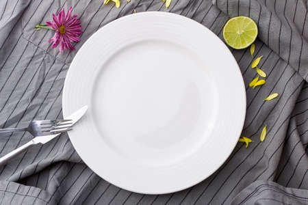 Empty dish ot grey tablecloth with flower and limeの写真素材