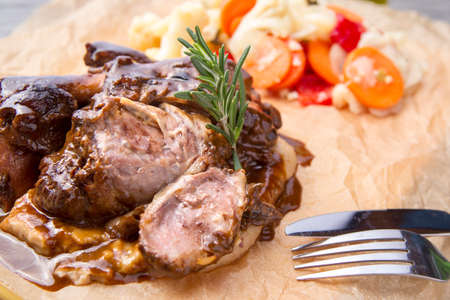 Roast pork shank with steamed vegetables and rosemary.