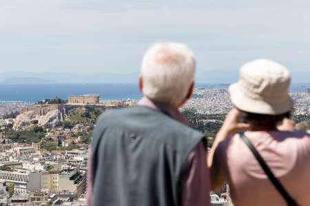 An elderly family couple are enjoying the view of Athens city, Greece.