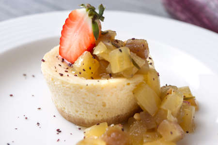 Cheesecake with aubergine jam and strawberry for decoration.の写真素材