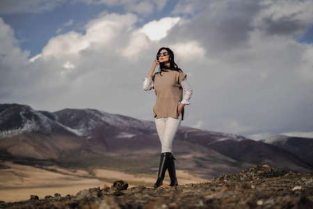 Beautiful stylish girl posing against the backdrop of white snowy peaks. Sunnyの写真素材