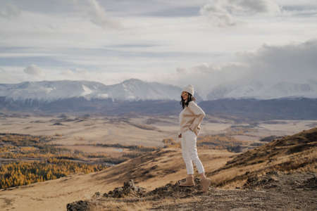 Beautiful stylish girl tourist posing against the backdrop of white snow peaks. Sunnyの写真素材