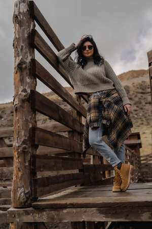 Brunette European girl posing in black glasses blue jeans and a plaid warm shirt. Wild West. Autumnの写真素材