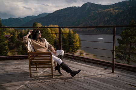 Beautiful girl in stylish light clothes and a brown hat sits on the roof and chillの写真素材
