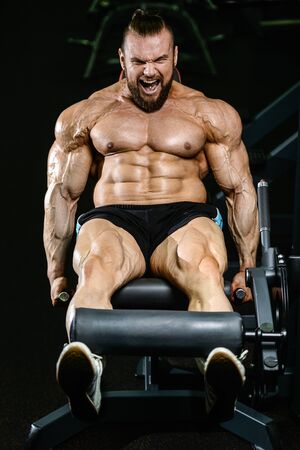 Handsome fit caucasian muscular man flexing his muscles in gym on diet. Brutal bodybuilder powerful training and execute exerciseの写真素材
