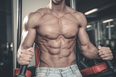 Handsome caucasian sexy fitness model in gym close up abs concept man on diet shirtless training six pack healthcare lifestyle crunchの写真素材