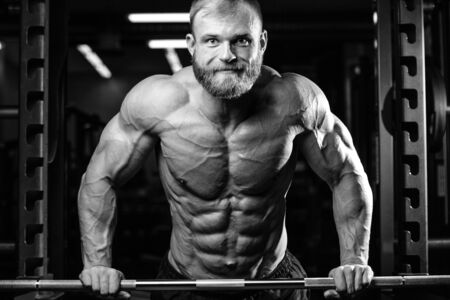Brutal bodybuilder on diet resting and working out in the gym. Caucasian sexy fitness male model...