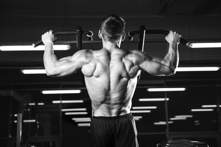 Handsome power athletic man on diet training pumping up back muscles pull up. Strong bodybuilder...