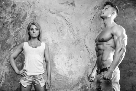 Beautiful young sporty sexy couple men and a woman posing showing muscle and workout in gymの写真素材