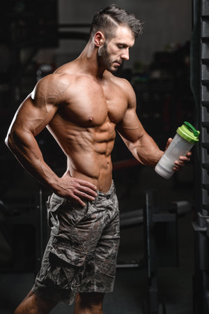 Muscular caucasian man on diet resting after exercise And drinking protein powder from shaker in the gymの写真素材