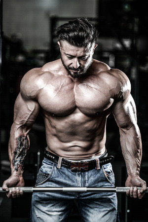 Handsome power athletic man on diet training pumping up muscles with dumbbell and barbell. Strong bodybuilder with six pack, perfect abs, shoulders, biceps, triceps and chestの写真素材
