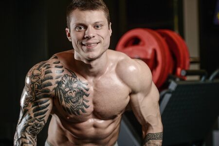 Strong and handsome athletic young tattoo man with muscles . Close-up of a power man on diet abs and biceps fitness and bodybuilding conceptの写真素材