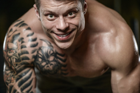 Strong and handsome athletic young tattoo man with muscles . Close-up of a power man on diet abs and biceps fitness and bodybuilding conceptの写真素材