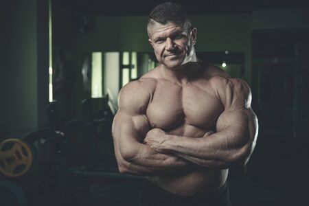 Brutal handsome Caucasian bodybuilder working out training in the gym gaining weight pumping up muscles and poses fitness and bodybuilding conceptの写真素材