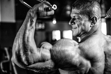 Handsome muscular Caucasian man of model appearance working out training arms in gym gaining weight pumping up muscles bicep and tricep with dumbbells and on machines fitness and bodybuilding conceptの写真素材