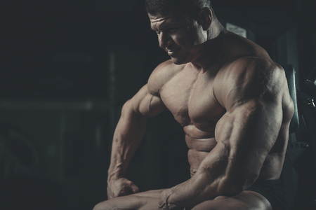 Brutal handsome Caucasian bodybuilder working out training in the gym gaining weight pumping up muscles and poses fitness and bodybuilding conceptの写真素材