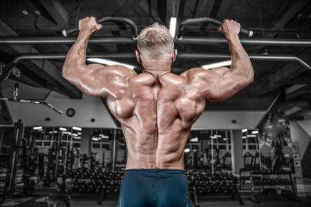 Handsome young muscular Caucasian man of model appearance working out training pumping up back lats...
