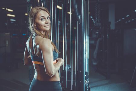 Beautiful sexy athletic young brunette Caucasian girl working out training in the gym gaining weight pumping up muscles and poses fitness and bodybuilding conceptの写真素材