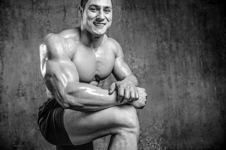 Handsome young muscular Caucasian man of model appearance posing in the gym gaining weight pumping up muscles and posesの写真素材