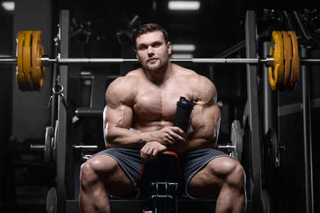 Brutal sexy strong bodybuilder athletic fitness man pumping up abs muscles workout bodybuilding concept background - muscular handsome men doing health care fitness exercises in gym naked torsoの写真素材