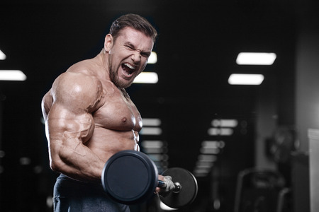 Brutal sexy strong bodybuilder athletic fitness man pumping up abs muscles workout bodybuilding...