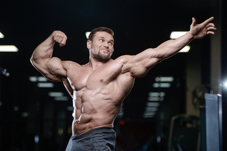 Brutal sexy strong bodybuilder athletic fitness man pumping up abs muscles workout bodybuilding concept background - muscular handsome men doing health care fitness exercises in gym naked torsoの写真素材