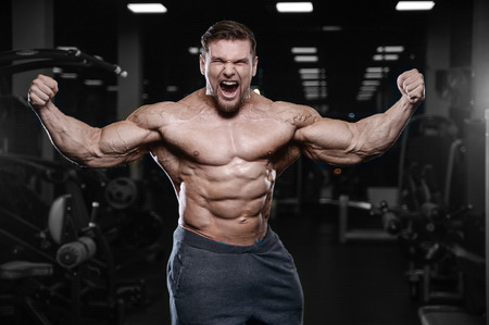 Brutal sexy strong bodybuilder athletic fitness man pumping up abs muscles workout bodybuilding concept background - muscular handsome men doing health care fitness exercises in gym naked torsoの写真素材