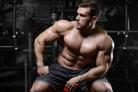Brutal sexy strong bodybuilder athletic fitness man pumping up abs muscles workout bodybuilding concept background - muscular handsome men doing health care fitness exercises in gym naked torsoの写真素材