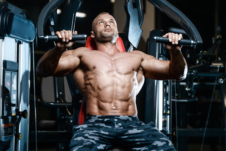 blonde brutal sexy strong bodybuilder athletic fitness man pumping up abs muscles workout...