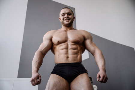 Brutal strong bodybuilder athletic fitness man pumping up abs muscles workout bodybuilding concept backgroundの写真素材