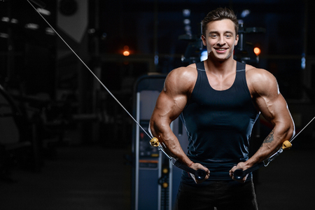 Handsome young fit muscular caucasian man of model appearance workout training in the gym gaining weightの写真素材