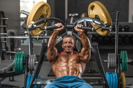 Brutal strong bodybuilder athletic aged man pumping up muscles workout bodybuilding concept background - muscular bodybuilder handsome men doing exercises in gym naked torso sport and diet conceptの写真素材
