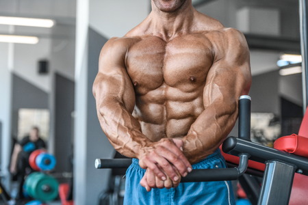 Brutal strong bodybuilder athletic aged man pumping up muscles workout bodybuilding concept background - muscular bodybuilder handsome men doing exercises in gym naked torso sport and diet conceptの写真素材