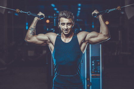 Handsome young fit muscular caucasian man of model appearance workout training in the gym gaining...