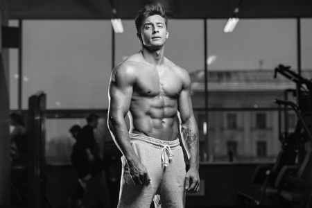 Handsome young fit muscular caucasian man of model appearance workout training in the gym gaining weight pumping up muscles and poses fitness and bodybuilding sport conceptの写真素材