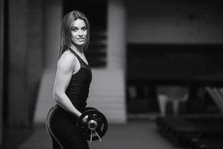Beautiful strong sexy athletic young caucasian fitness girl with long hair workout training in the gym pumping up abs muscles and posing bodybuilding health care diet and fitness sport conceptの写真素材